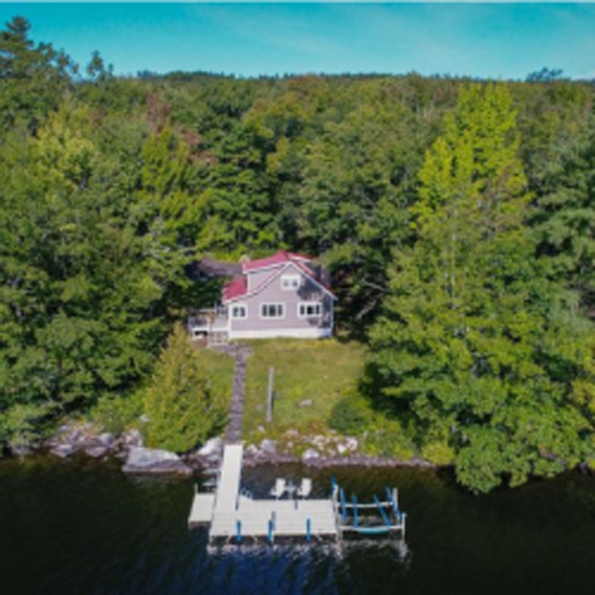 Arial wide shot of beige house and dock on the water