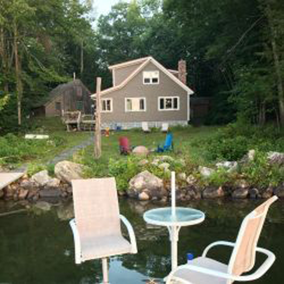 Two chairs on the dock in the foreground, looking towards backyard of the house